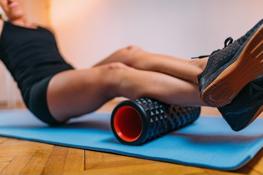 Masserar vadmusklerna med en foam roller sittandes på en matta