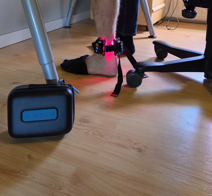 Kineon Move+ placerad direkt över hälsenan med rött ljus som lyser upp golvet runtomkring