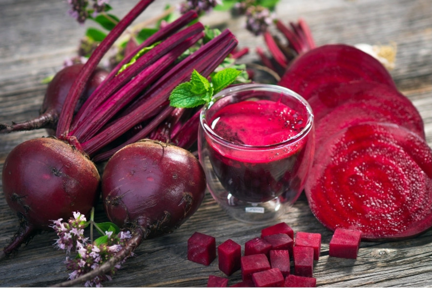 Nyupptagna rödbetor på ett bord, med skivor och kuber samt ett glas rödbetsjuice